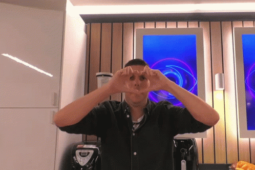 A Man Is Making A Heart Shape With His Hands In Front Of A Blender GIF