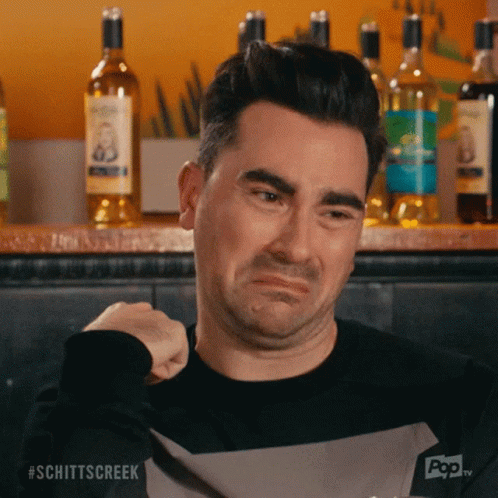 A Man Is Making A Sad Face In Front Of Bottles Of Alcohol . GIF