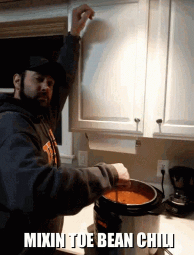 A Man Is Mixing Bean Chili In A Pot GIF