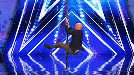 A Man Is On A Pole On A Stage With A Blue Background GIF