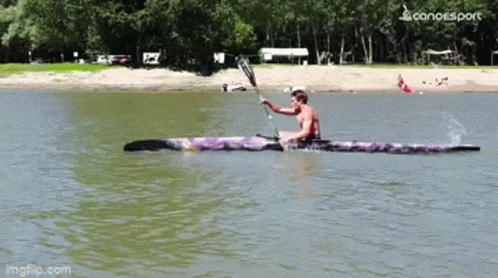 A Man Is Paddling A Purple Kayak On A Lake With A Canoesport Logo In The Corner GIF