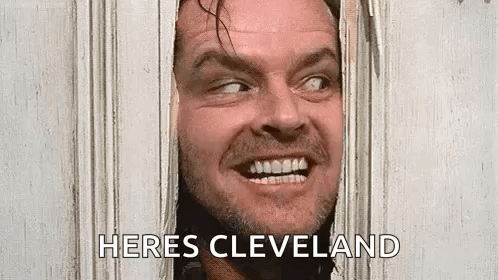 a man is peeking through a hole in a door and smiling .