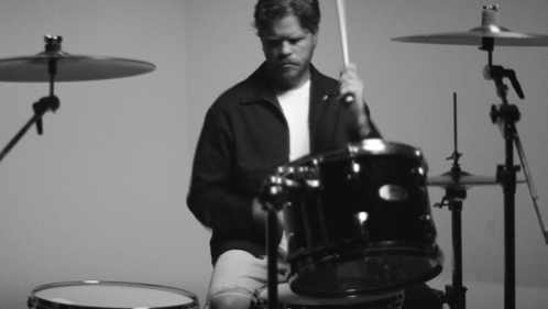 A Man Is Playing A Drum Set With A Sabian Cymbal In The Background GIF