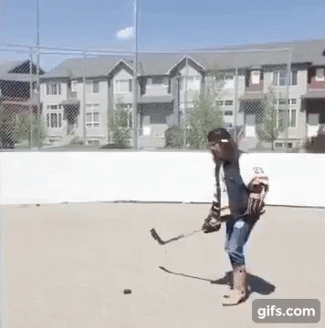 A Man Is Playing A Game Of Ice Hockey On A Concrete Rink . GIF