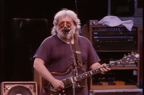 A Man Is Playing A Guitar And Singing Into A Microphone . GIF