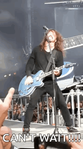 A Man Is Playing A Guitar And Singing Into A Microphone With The Words Can 'T Wait Written Below Him GIF