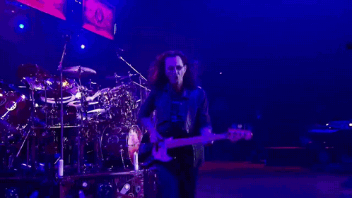 A Man Is Playing A Guitar In A Dark Room GIF
