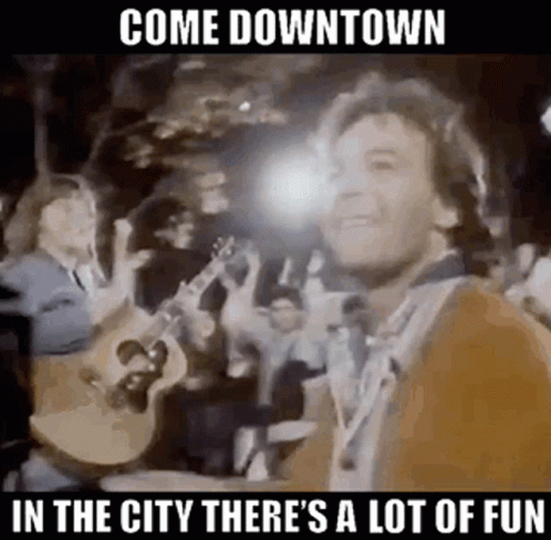 A Man Is Playing A Guitar In Front Of A Crowd Of People While Standing In Front Of A Crowd . GIF