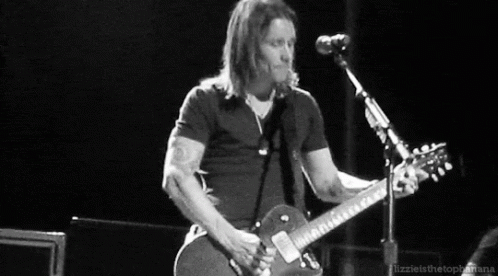 a man is playing a guitar in front of a microphone .