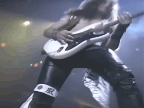 A Man Is Playing A Guitar On A Stage While Wearing A Bandage With Chinese Characters On It . GIF