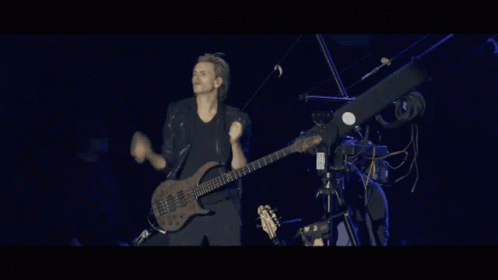 a man is playing a guitar on a stage with a camera behind him