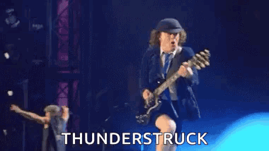 A Man Is Playing A Guitar On A Stage With The Words `` Thunderstruck '' Behind Him . GIF