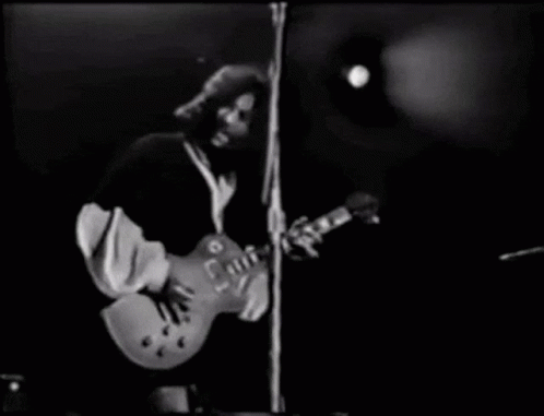A Man Is Playing A Guitar On Stage In A Black And White Photo . GIF