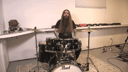 A Man Is Playing A Pearl Drum Set In A Room GIF