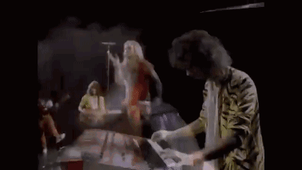 A Man Is Playing A Piano And Holding A Piece Of Paper In His Hands . GIF