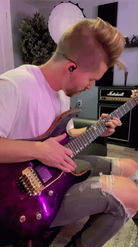 A Man Is Playing A Purple Guitar In Front Of A Marshall Amp GIF