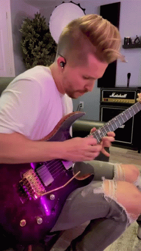 A Man Is Playing A Purple Guitar In Front Of A Marshall Amp GIF