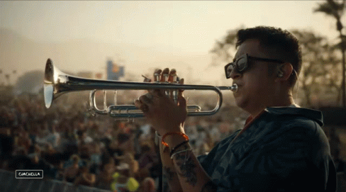 A Man Is Playing A Trumpet In Front Of A Crowd At A Music Festival Called Cancabella GIF