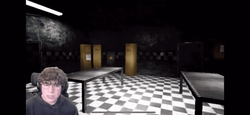 A Man Is Playing A Video Game In A Dark Room With Checkered Floors GIF