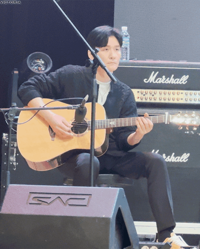 A Man Is Playing An Acoustic Guitar In Front Of A Marshall Amplifier GIF