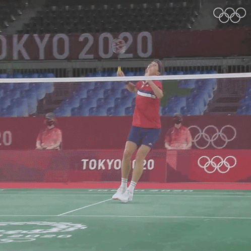 A Man Is Playing Badminton In Front Of A Tokyo 2020 Sign GIF