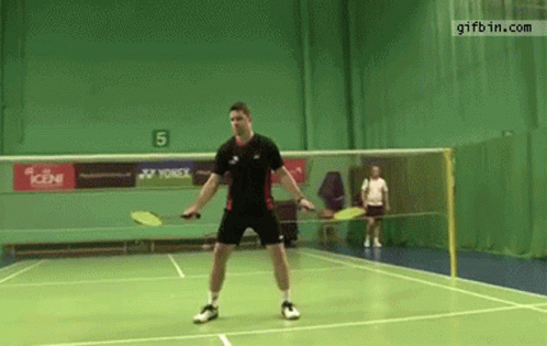 A Man Is Playing Badminton On A Court With A Yonex Advertisement On The Wall GIF