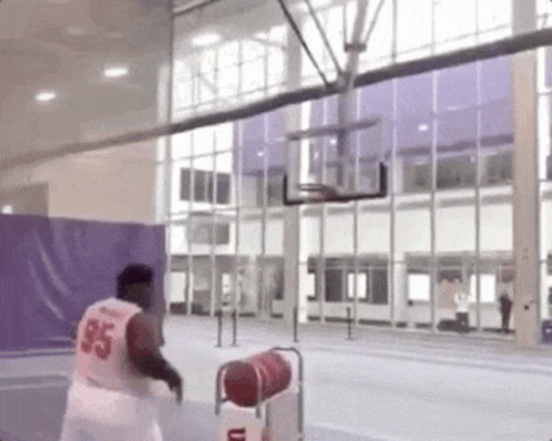 A Man Is Playing Basketball In A Gym With A Basketball Hoop . GIF