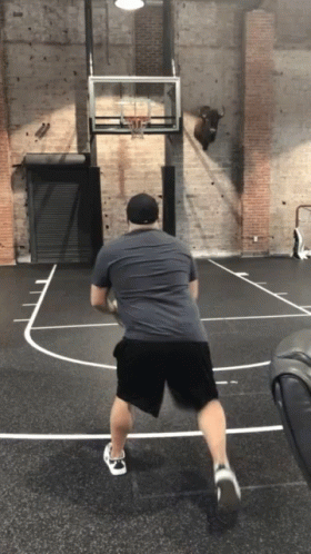 A Man Is Playing Basketball On A Court With A Bull On The Wall GIF