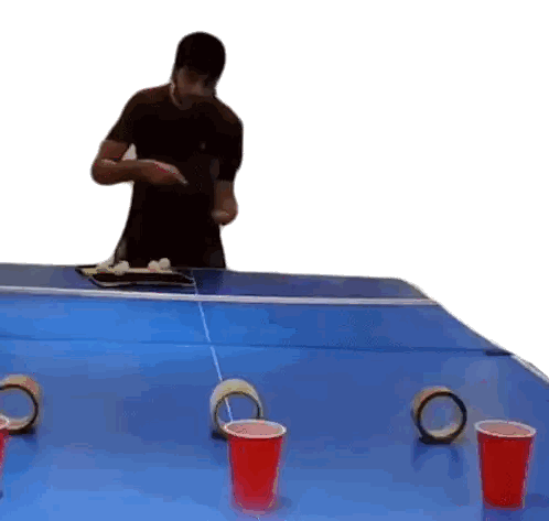 a man is playing beer pong with red cups and tape