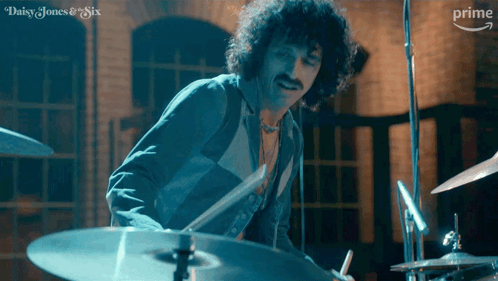 A Man Is Playing Drums In A Daisy Jones And Six Ad GIF
