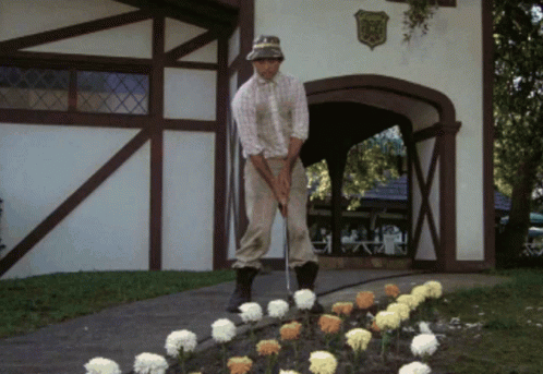A Man Is Playing Golf In Front Of A Building With A Shield On It That Says ' Eagle ' On It GIF