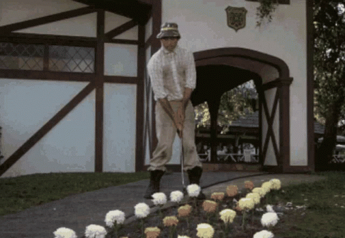 A Man Is Playing Golf In Front Of A Building With A Shield On It That Says ' Eagle ' GIF