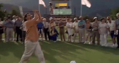 A Man Is Playing Golf On A Green While A Crowd Watches . GIF