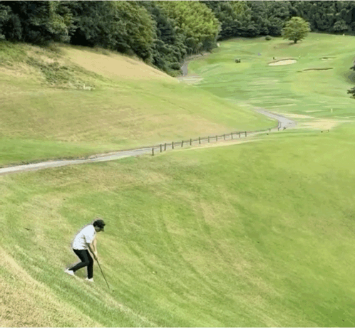 A Man Is Playing Golf On A Hill With A Fence In The Background GIF