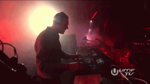 A Man Is Playing Music In A Dark Room With A Sign That Says Umf Tu GIF