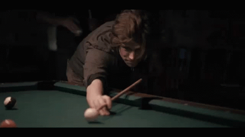 A Man Is Playing Pool In A Dark Room With A Pool Cue And Ball . GIF