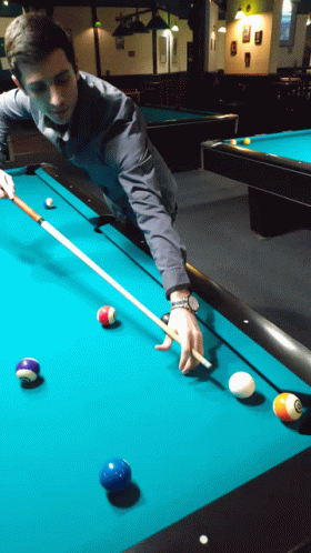 A Man Is Playing Pool With A Cue And Balls On The Table GIF