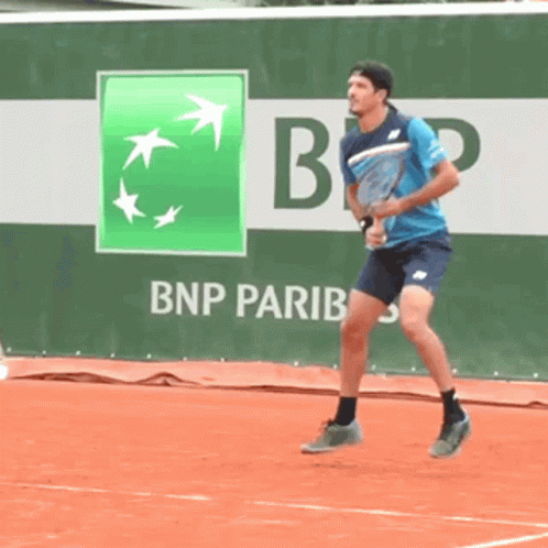 a man is playing tennis in front of a bnp pariba ad