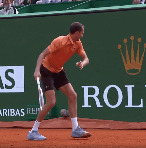 A Man Is Playing Tennis In Front Of A Rolex Ad GIF