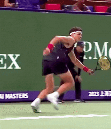 A Man Is Playing Tennis In Front Of A Rolex Advertisement GIF