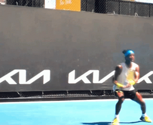 A Man Is Playing Tennis In Front Of A Sign That Says Km GIF