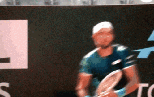 A Man Is Playing Tennis In Front Of A Top Sign GIF