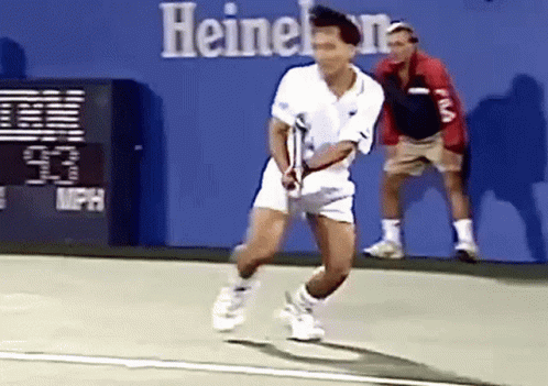 A Man Is Playing Tennis On A Court In Front Of A Sign That Says Heineken GIF