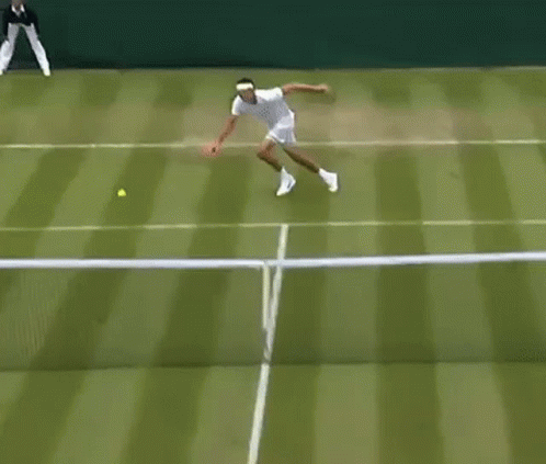 A Man Is Playing Tennis On A Tennis Court While A Referee Stands Behind Him . GIF