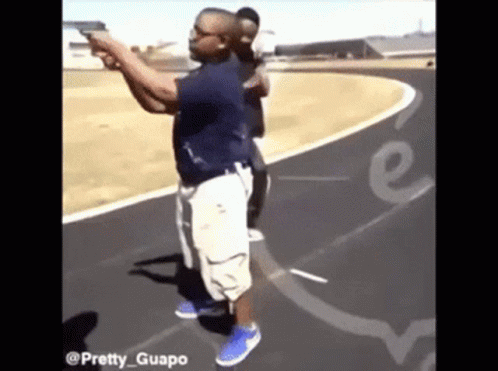 A Man Is Pointing A Gun At Another Man On A Track With The Words Pretty Guapo On The Bottom GIF