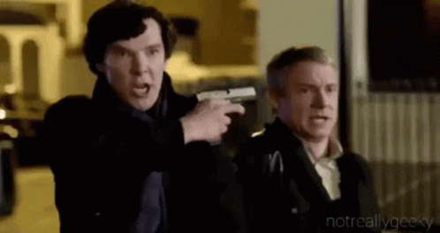 A Man Is Pointing A Gun At Another Man While They Are Standing Next To Each Other . GIF