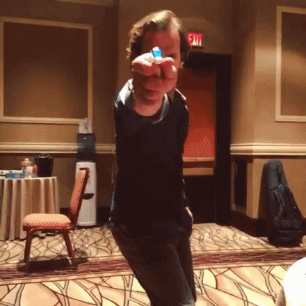 A Man Is Pointing At The Camera With A Blue Object In His Hand GIF