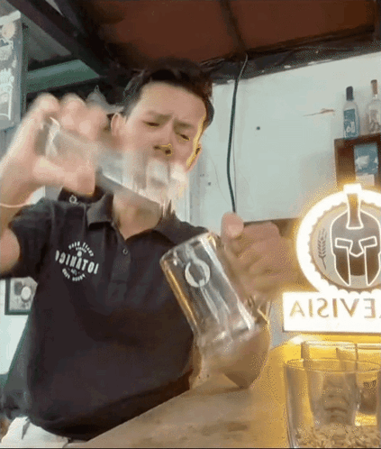 A Man Is Pouring A Drink Into A Glass In Front Of A Sign That Says ' Ai2ive ' On It GIF