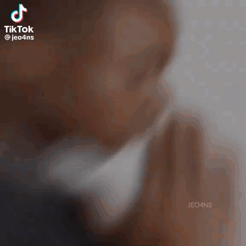 A Man Is Praying With His Hands Folded In Front Of His Face GIF