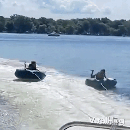 A Man Is Pulling A Boat With A Jet Ski Attached To It On A Lake . GIF